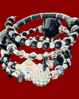 Stack of black and silver beaded bracelets on a red background