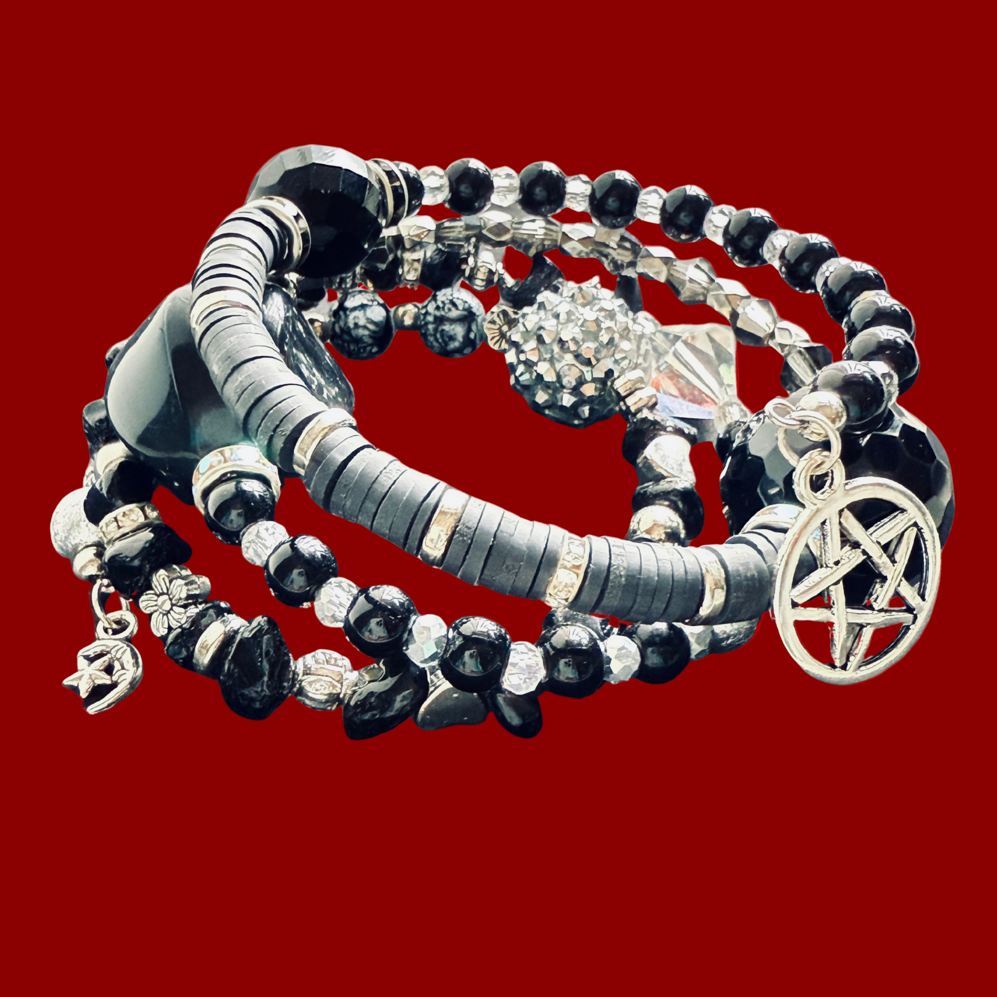 Set of black and silver beaded bracelets with pentacle charm on a red background